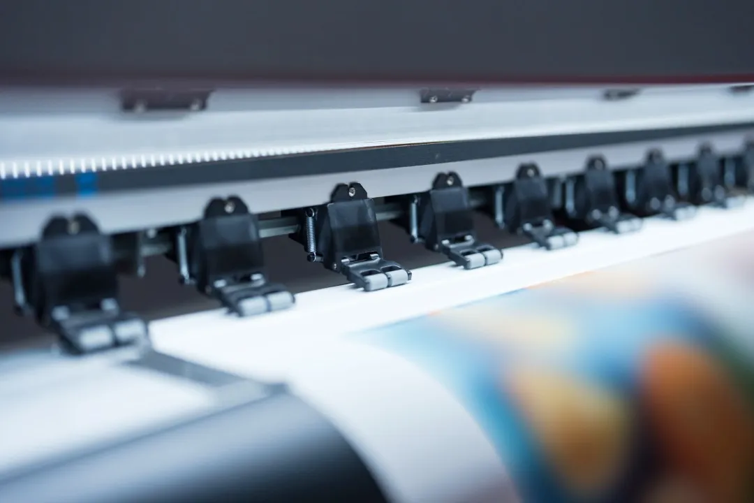 Cabezal de una impresora de inyección de tinta de gran formato aplicando tinta a un rollo de vinilo en un centro de impresión digital.