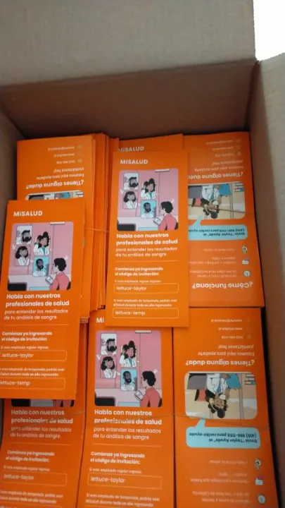 Una caja llena de folletos impresos para MISALUD, mostrando el producto terminado en un centro de impresión digital.
