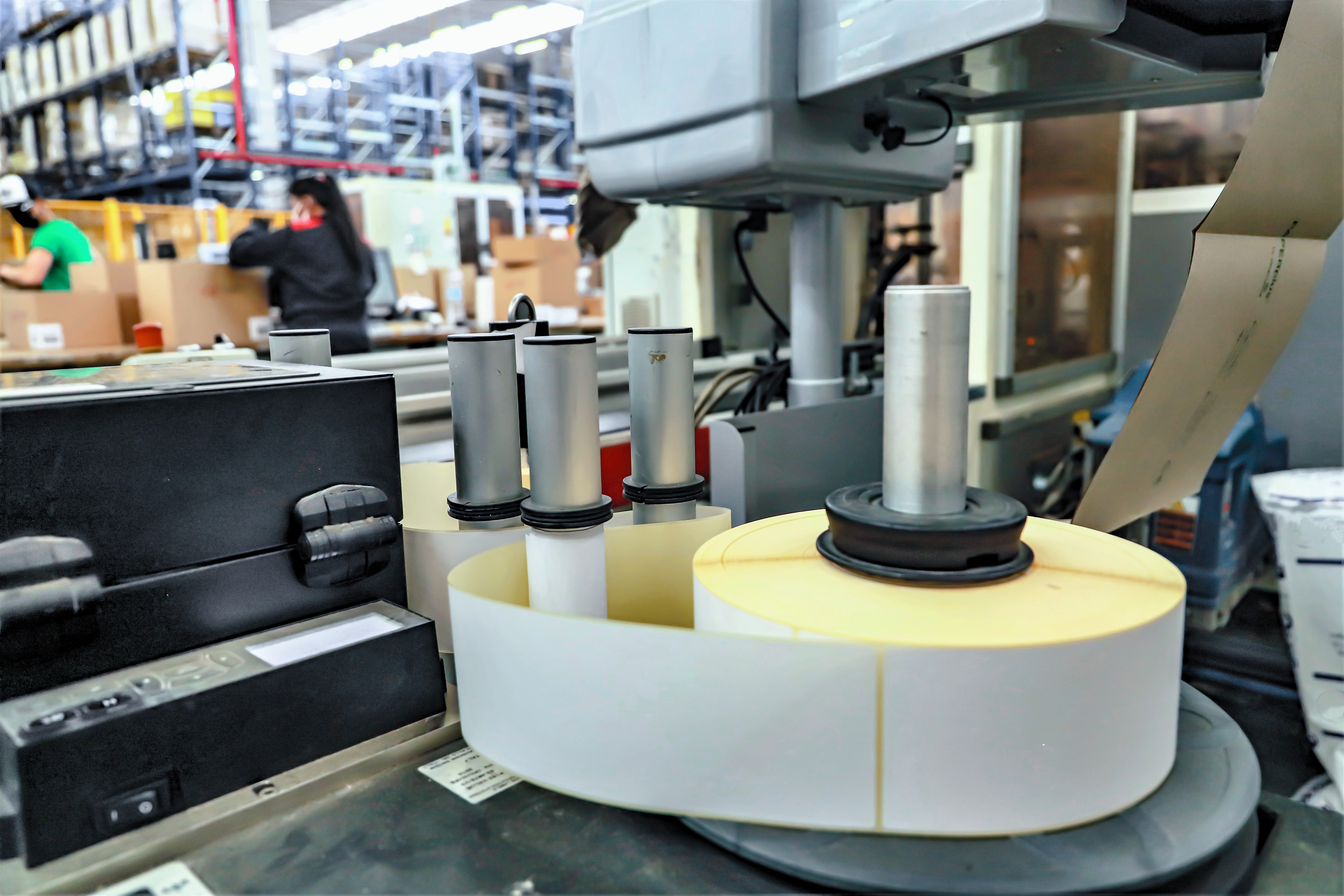 Proceso industrial de impresión y rebobinado en rollos dentro de una fábrica de etiquetas