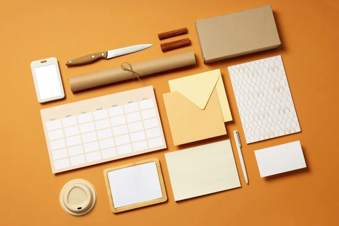 Kit de papelería corporativa en tonos beige y blanco con calendario, tarjetas y elementos naturales.