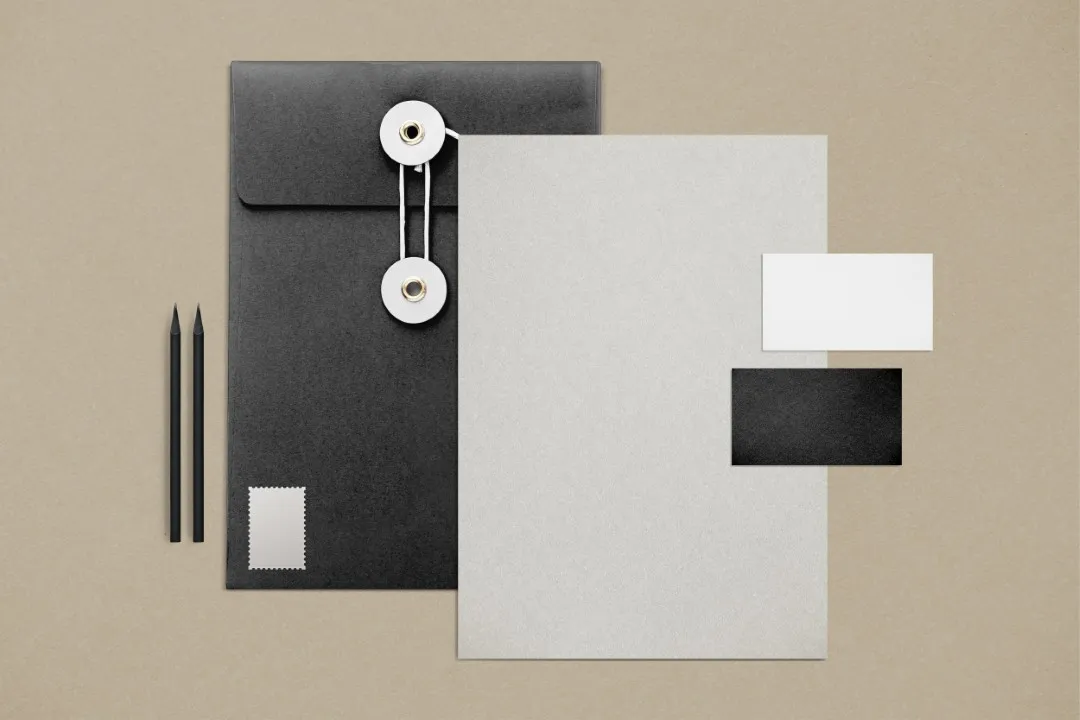 Papelería corporativa elegante en negro y kraft con cuadernos, clips, calculadora y regla.